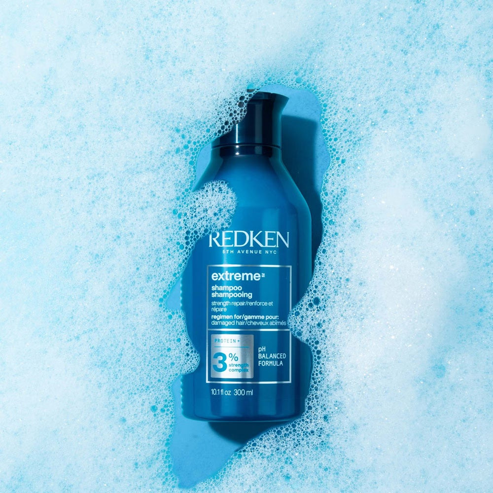Redken Extreme Shampoo bottle surrounded by blue lather